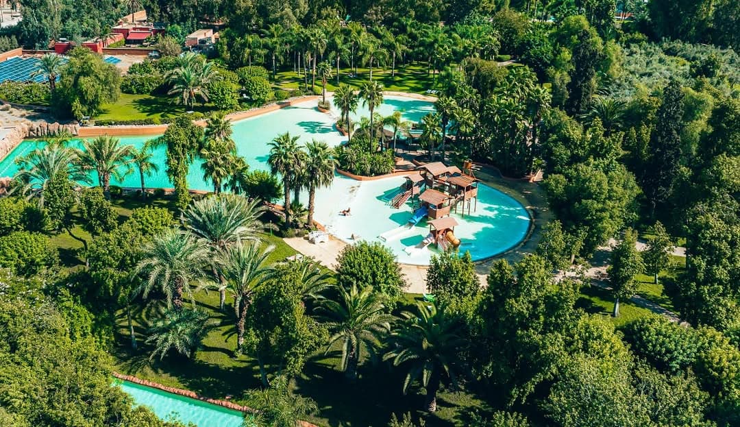 Vue aérienne des piscines tropicales d'Oasiria entourées de palmiers